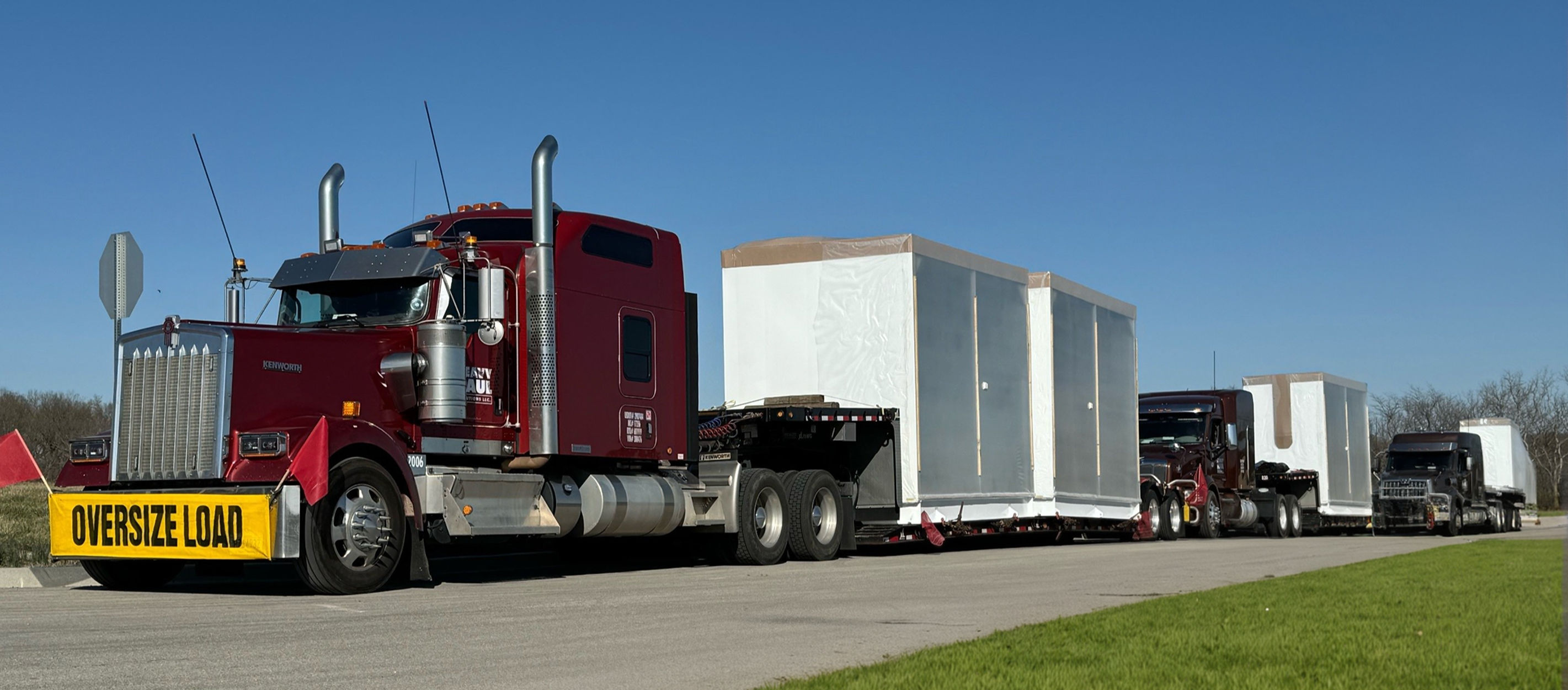 Red Kenworth hauling a white oversize modular load