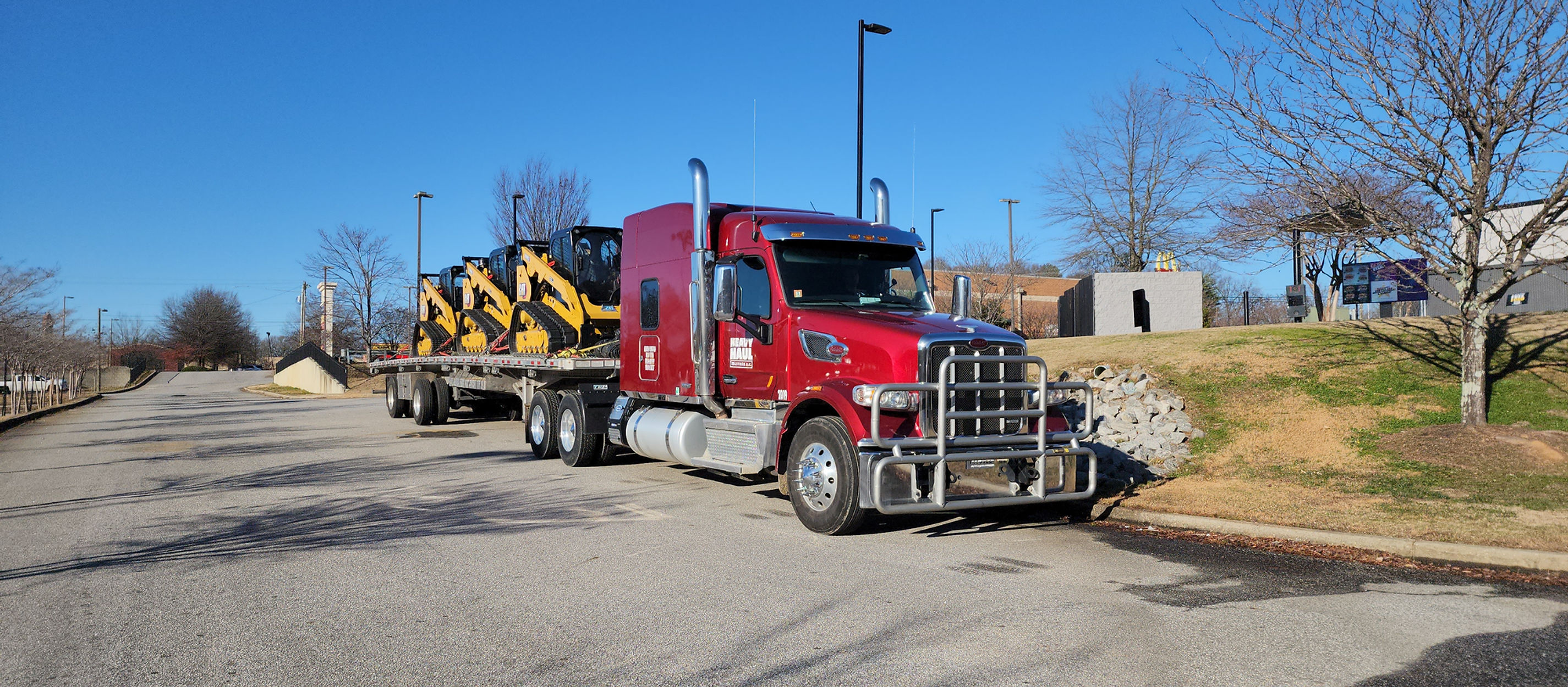 Red flatbed semi loaded with yellow compact excavators