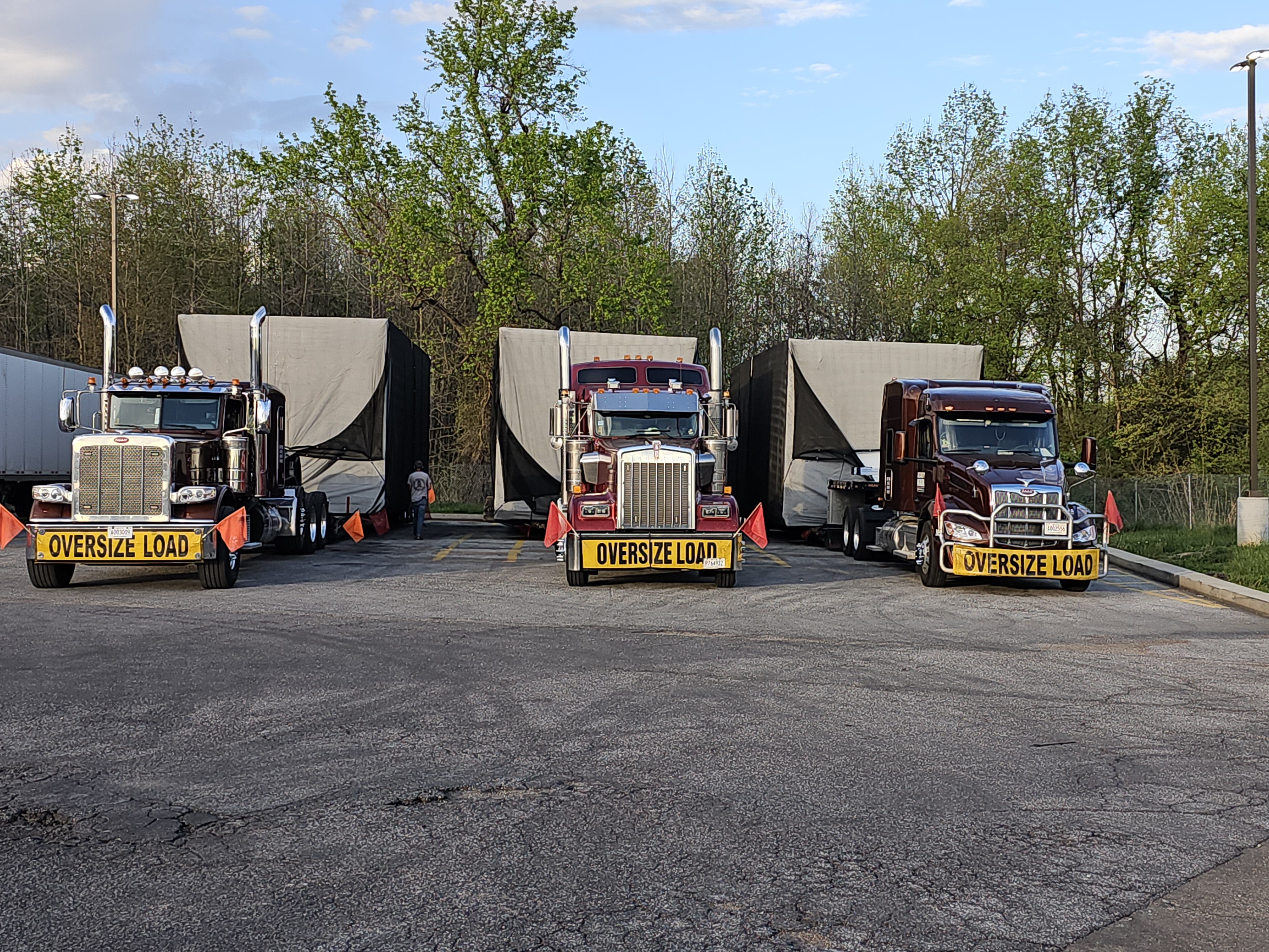 Three HHS heavy-haul trucks with OVERSIZE LOAD banners lined up hauling oversized loads