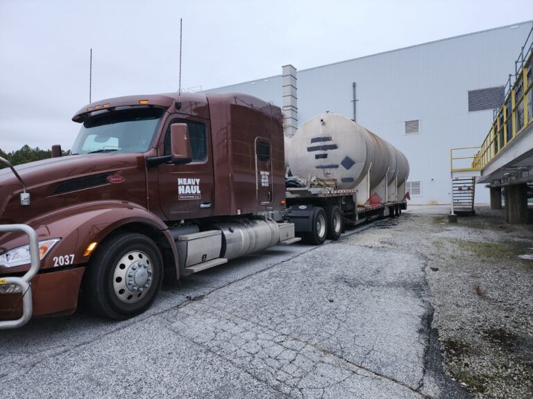 Heavy Haul Solutions semi tractor with tank trailer parked at industrial facility with loading dock