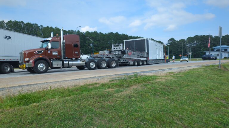 Semi tractor with Aspen perimeter trailer hauling large white industrial module
