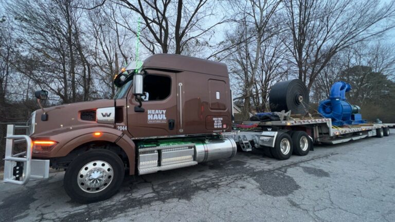 Heavy Haul Solutions semi truck with lowboy trailer parked with large industrial equipment loaded on the bed