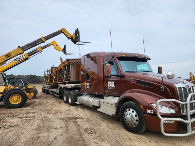 Heavy Haul Solutions truck with stepdeck trailer parked beside material handler and wheel loader at work site