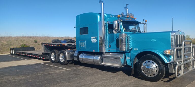 Heavy Haul Solutions semi tractor with RGN trailer parked on roadside near arid terrain.