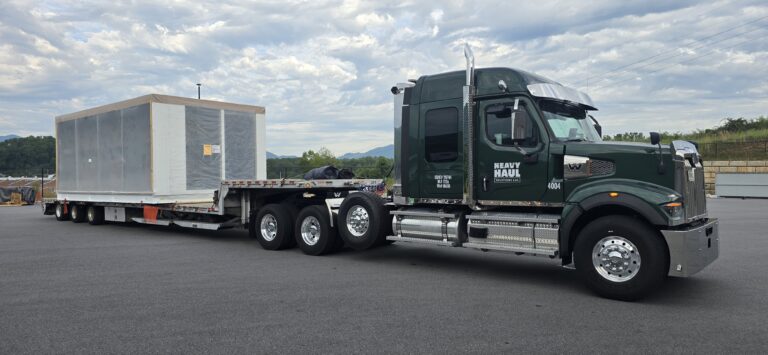 Heavy Haul Solutions semi tractor with enclosed trailer parked in lot, mountains visible in distance.