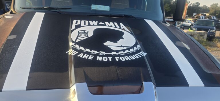Hood of a truck with white racing stripes and a POW/MIA flag decal stating 'You are not forgotten