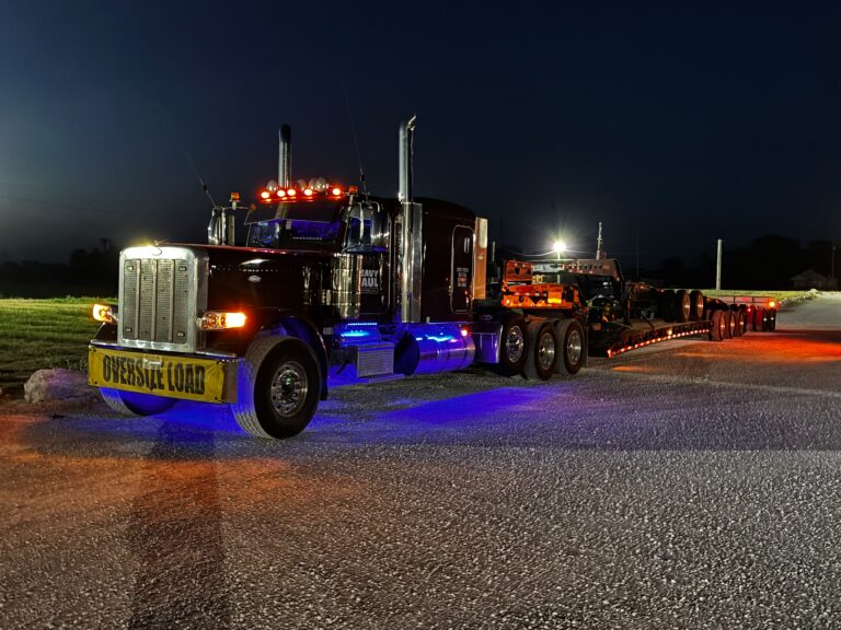 Oversized load truck parked at night with blue and orange lighting, specialized RGN trailer