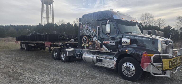 Heavy Haul Solutions semi tractor with flatbed trailer parked in a yard with a water tower visible in the background.