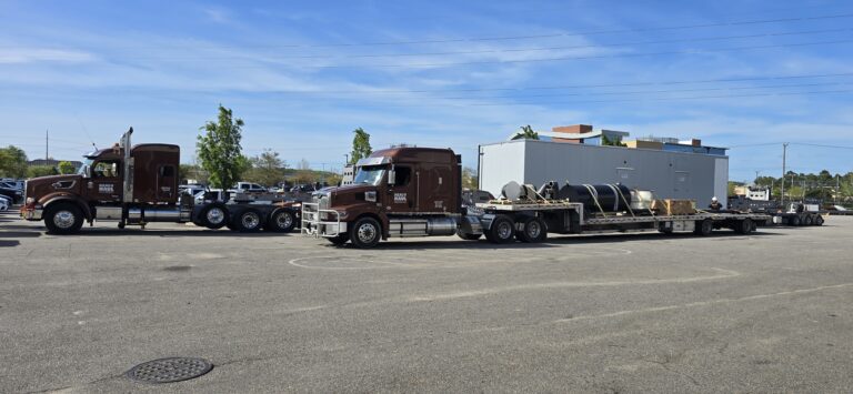 Heavy Haul Solutions tractors with perimeter trail and step deck trailers parked in a yard.