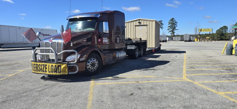 Semi tractor with oversized load sign hauling trailer with modular building.